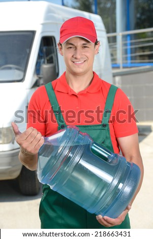 Smiling young male delivery courier man in front of cargo van delivering bottles of water