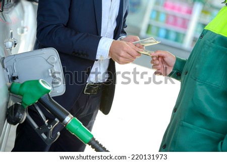 Businessman give money dispensers, filled car on gas station