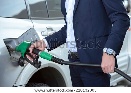 Young businessman refueling car tank at fuel station