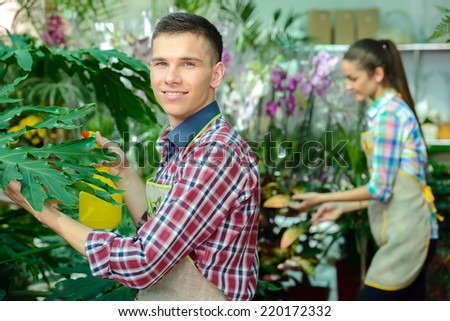 Young smiling florists man and woman working in the greenhouse.
