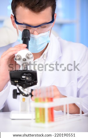 Serious clinician studying chemical element in laboratory using a microscope