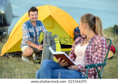 Attractive happy woman sitting near tent cities holding book on a sunny day