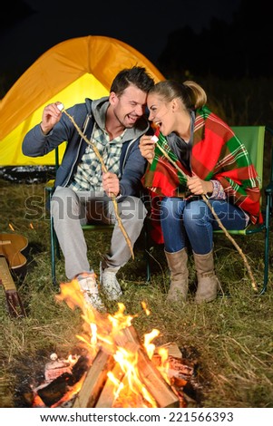 Tent camping couple romantic sitting by bonfire night countryside