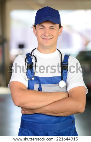 Handsome mechanic working in auto repair shop with a stethoscope around his neck. concept doctor for cars