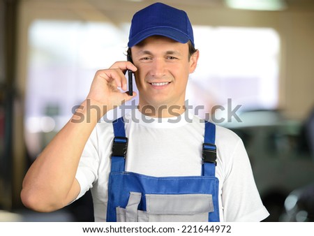 Auto mechanic using mobile phone in workshop. atoservis background
