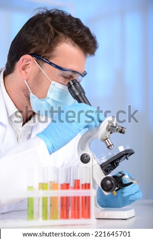 Serious clinician studying chemical element in laboratory using a microscope