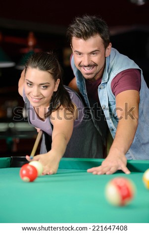 Young couple plays billiards in the dark billiard club