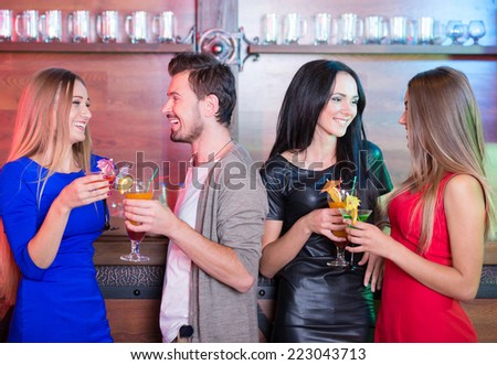Portrait of happy friends holding glasses with cocktails in bar