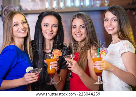 Party, celebration, friends, bachelorette and birthday concept - three beautiful woman in evening dresses with cocktails