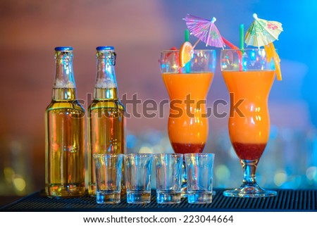 Different alcohol drinks and cocktails on bar. colored light