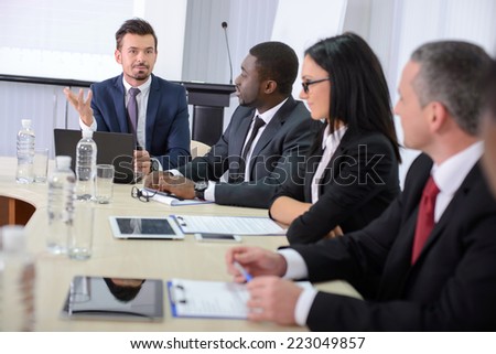 Business conference. Business meeting. Business people in formalwear discussing something while sitting together at the table