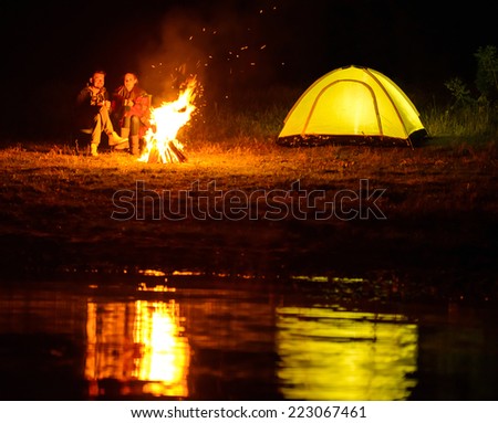 Romantic evening. A charming couple, camping, sitting around the campfire