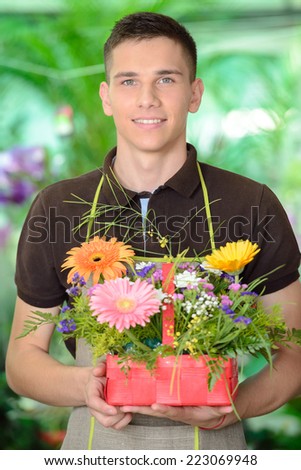 Portrait of a young man florist that cares for the flowers in the greenhouse