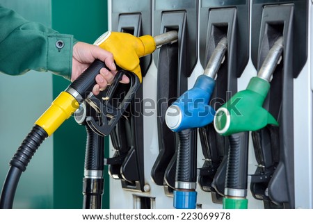 Close-up of a men\'s hand using a fuel nozzle at a gas station. Petrol station. Filling station. Petrol. Gasoline.