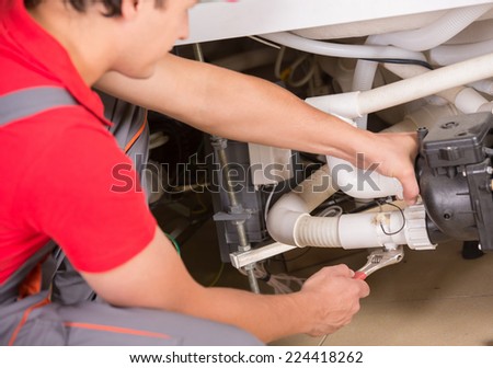 Young professional plumber with a wrench. Clogged sink.