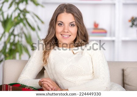 Portrait of woman lying on sofa. Casual style indoor shoot. Happy smiling relaxing girl on living room background.