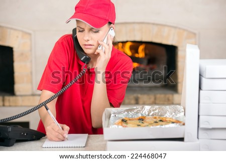 Close-up delivery women write the ordered pizza for delivery.