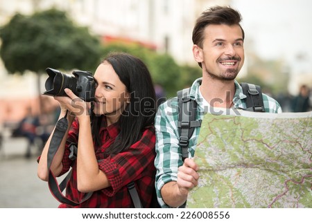 Two young tourists with backpacks, touristic map and camera. Sightseeing City.