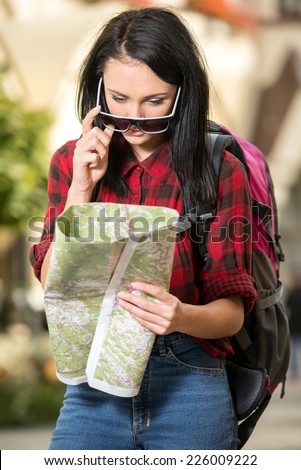 Young woman is looking for a place on the map in the town.