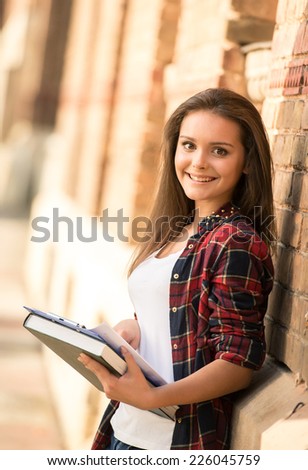 Portrait of a young attractive female student with university building in the background.