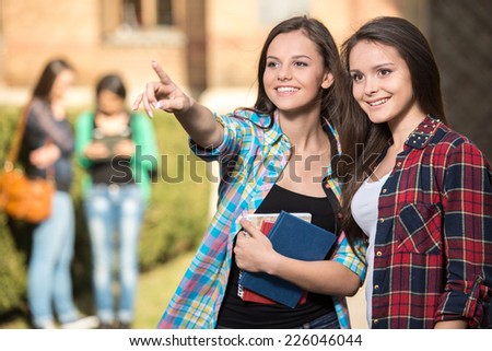 Portrait of two female students at the college, outdoors. The students in the background.