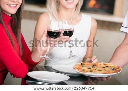 Happy women raises her glass of red wine for a toast. Close-up.