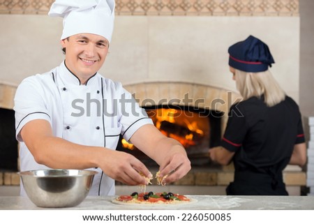 Two chefs, man and woman are at the work in a pizzeria.