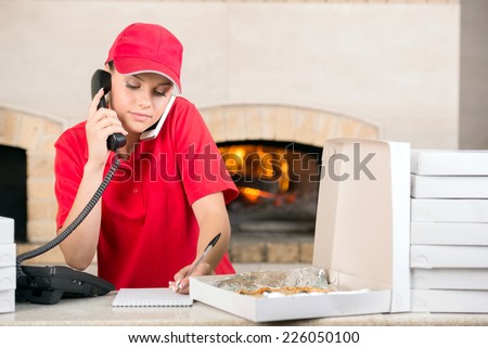 Woman in red is working as delivery girl in a pizza place holding.