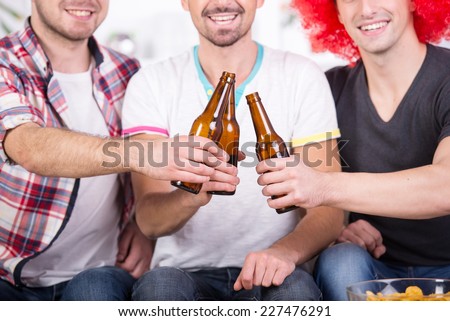 Group of sports fans are watching game on TV at home and drinking beer.