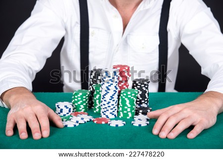 Poker player, on a black background, with poker chips on the table.