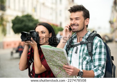 Two happy young tourists with backpacks, touristic map and camera. Sightseeing City.