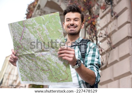 Smiling young tourist man with a map of the city.