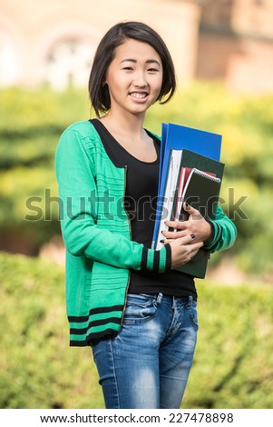 Portrait of a young beautiful asian student with university building in the background.