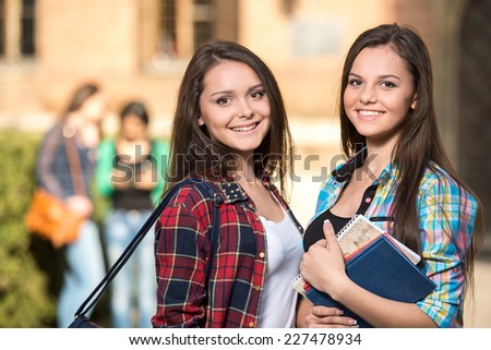 Portrait of two female students at the college, outdoors. The students in the background.