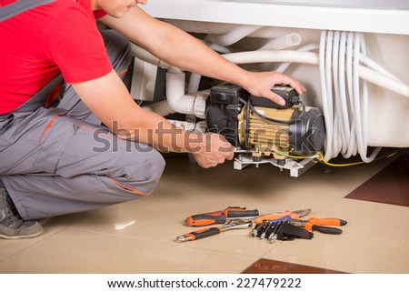 Male plumber fixing sink pipe in bathroom.