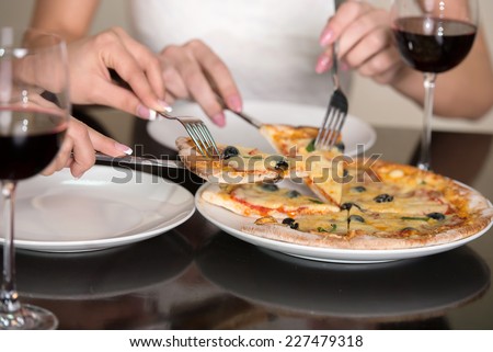 Women eats pizza. Close-up olives and cheese italian pizza with fork and knife and wine.