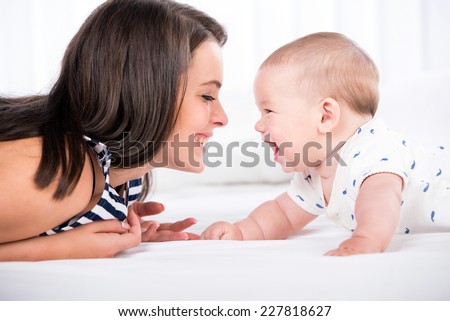 Beautiful mother and son are lying in bed and looking at each other.