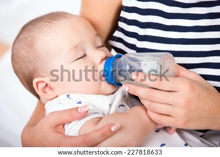 Portrait of a mother is  feeding her little baby boy from the milk bottle.