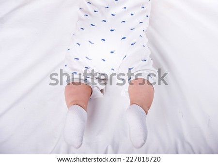 Close-up of the charming small legs of  a baby is lying on the bed.
