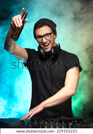 Portrait of a young dj with mixer, on foggy background.