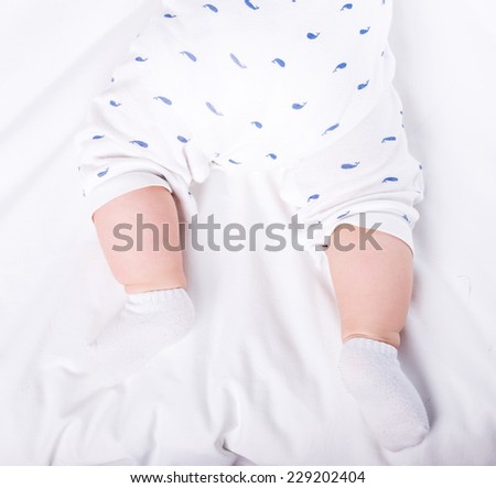 Close-up of the charming small legs of  a baby is lying on the bed.