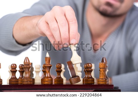 Close-up  hand with chess is making the move on the white background.