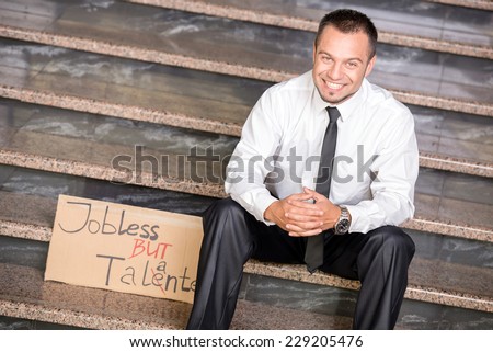 Creative young man is sitting on the stairs with a sign. He is looking for a job.