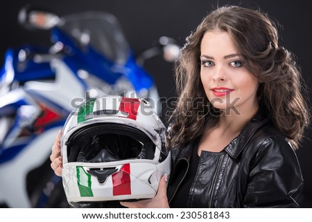 Portrait of young attractive girl with helmet. The motorcycle is on black background.