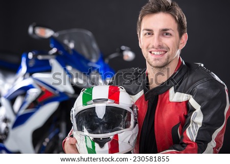 Portrait of young smiling man with helmet. The motorcycle is on black background.