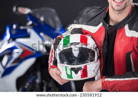 Portrait of smiling man with helmet. The motorcycle is on black background.
