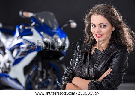 Portrait of young attractive girl and motorcycle on black background.