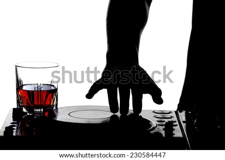 Close-up hand of a dj on the turntables and a glass of alcohol.