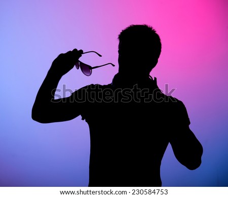 Silhouette of a man. Portrait of a young man with sunglasses on colored background.
