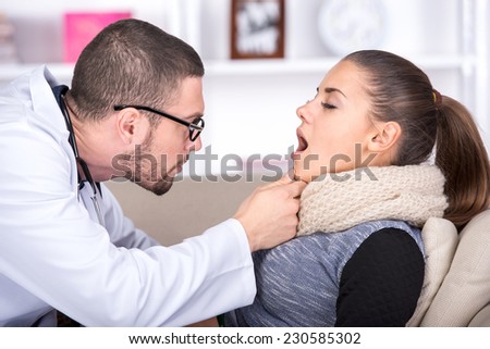 General practitioner examining mouth and throat of a patient with cold.